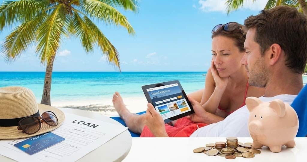 Valiză și accesorii de plajă lângă bani și calculator, concept vizual pentru creditul de vacanță.